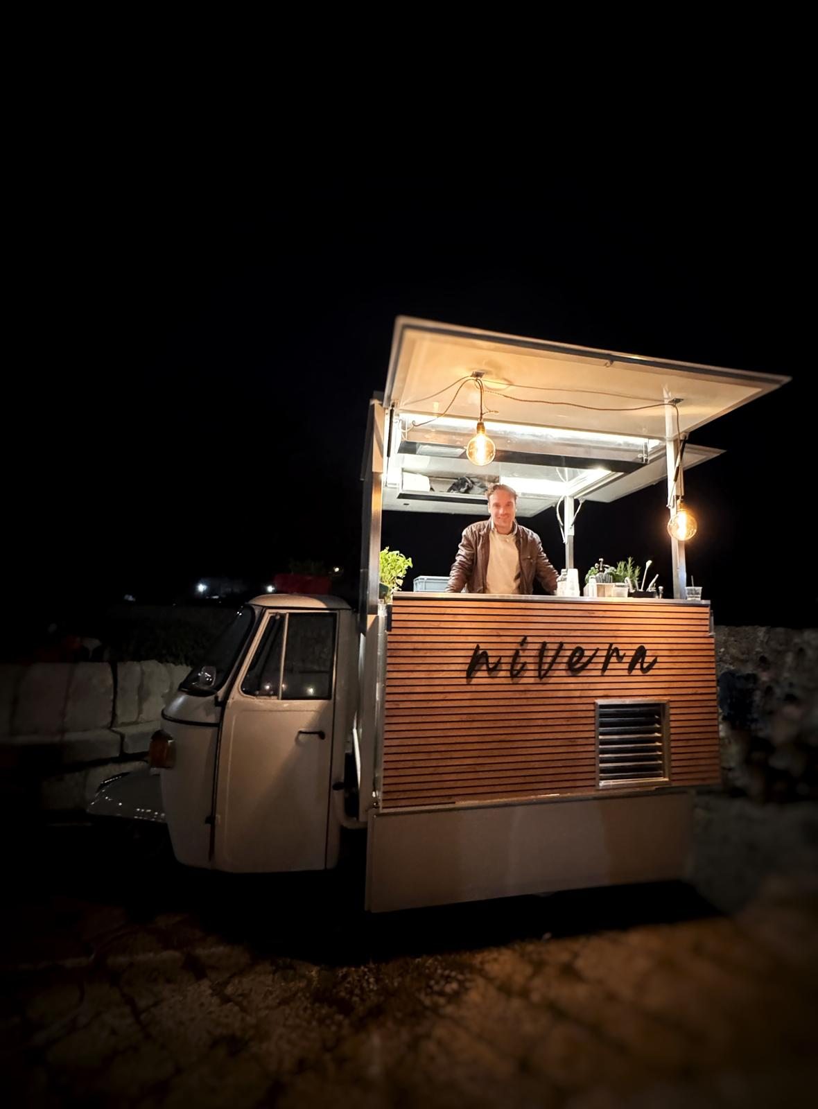 Bar Nivera illuminato di notte con bartender al lavoro